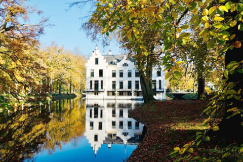 Manoir élégant au bord d’un lac entouré d’arbres d’automne, parfait pour un séjour glamping pittoresque.