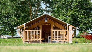 Safari tent Villatent Compact at Camping Betuwe in the Netherlands, surrounded by lush grass and trees.