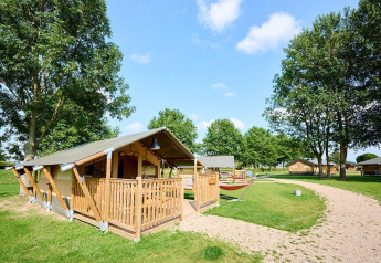 Tenda safari Villatent Compact al Camping Betuwe nei Paesi Bassi, circondata da alberi e prato verde.