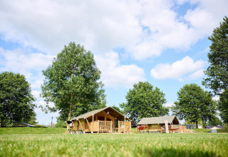 Safaritent Villatent Compact op Camping Betuwe in Nederland, omringd door bomen en een groene grasmat.