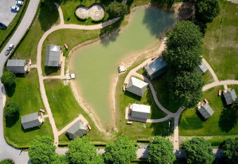 Vista aerea delle tende safari Villatent Compact accanto a uno stagno al Camping Betuwe, Paesi Bassi, con sentieri.