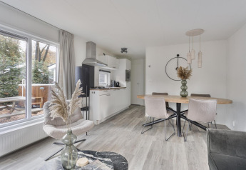 Moderne lodge med spisebord, køkken og store vinduer med udsigt til naturen ved De Thijmse Berg i Holland.