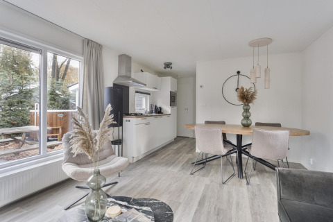 Modern lodge interior with dining table, kitchen, and large windows at Wellness Lodge, De Thijmse Berg, Netherlands.