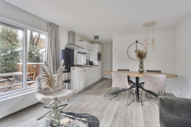 Modern lodge interior with dining table, kitchen, and large windows at Wellness Lodge, De Thijmse Berg, Netherlands.