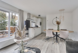 Modern lodge interior with dining table, kitchen, and large windows at Wellness Lodge, De Thijmse Berg, Netherlands.