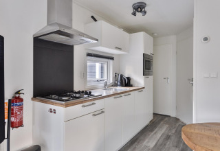 Modern lodge kitchen with white cabinets, gas stove, and built-in appliances at De Thijmse Berg, Netherlands.