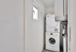 Compact laundry room with stacked washer and dryer at Wellness Lodge | 2 persons, De Thijmse Berg, Netherlands.