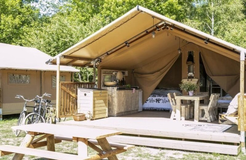 Tente safari au Holiday park Witterzomer aux Pays-Bas, avec terrasse en bois, vélos et table de pique-nique.