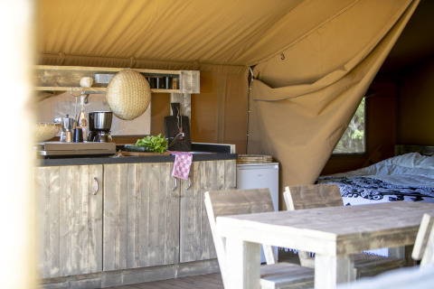 Interior de tienda safari con cocina rústica y mesa en el Holiday park Witterzomer, Países Bajos.