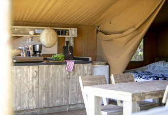 Interiør af Safari-telt med rustikt køkken og spisebord på Holiday park Witterzomer, Holland.