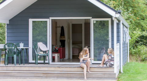 Twee meisjes zitten pratend op de veranda van een chalet bij Holiday park Witterzomer in Nederland.