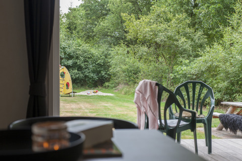 Uitzicht vanuit chalet met veranda over tuin, plastic stoelen en speeltuintje bij Holiday park Witterzomer.