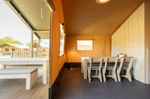 Vista interior de una tienda safari Villatent Nomad con comedor en Vakantiepark de Twee Bruggen, Países Bajos.
