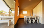Vista interior de una tienda safari Villatent Nomad con comedor en Vakantiepark de Twee Bruggen, Países Bajos.