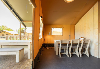 Vista interior de una tienda safari Villatent Nomad con comedor en Vakantiepark de Twee Bruggen, Países Bajos.