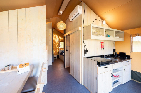 Vista interior de una tienda safari Villatent Nomad con cocina en Vakantiepark de Twee Bruggen, Países Bajos.