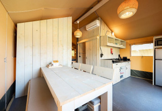 Vista interior de una tienda safari Villatent Nomad con comedor y cocina en Vakantiepark de Twee Bruggen.