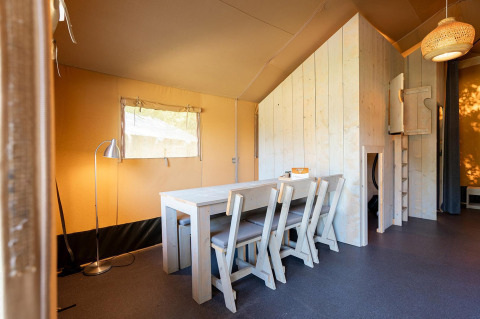 Vista interior de una tienda safari Villatent Nomad con mobiliario de madera en Vakantiepark de Twee Bruggen, Países Bajos.