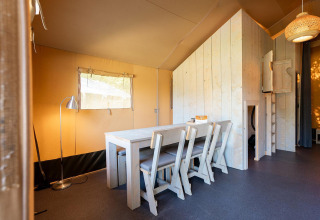 Vista interior de una tienda safari Villatent Nomad con mobiliario de madera en Vakantiepark de Twee Bruggen, Países Bajos.