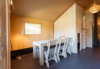 Interior view of a Villatent Nomad safari tent with wooden furniture at Vakantiepark de Twee Bruggen, Netherlands.