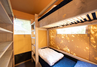 Vista interior de una tienda safari Villatent Nomad con literas y estanterías en Vakantiepark de Twee Bruggen.