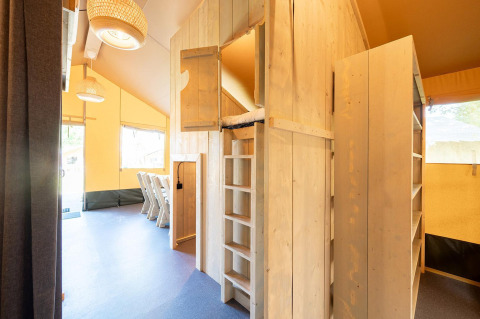 Intérieur de tente safari Villatent Nomad au Vakantiepark de Twee Bruggen, bois et coin repas.