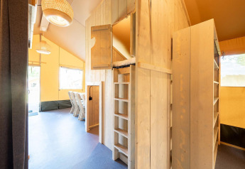 Intérieur de tente safari Villatent Nomad au Vakantiepark de Twee Bruggen, bois et coin repas.