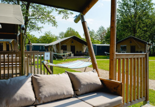 Tienda safari Villatent Nomad con terraza, hamaca y césped en Vakantiepark de Twee Bruggen, Países Bajos.