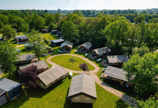 Vista aérea de tiendas safari en Villatent Nomad en Vakantiepark de Twee Bruggen, Países Bajos, rodeadas de árboles.