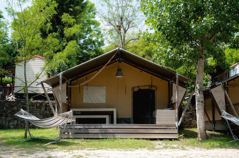 Safaritent Villatent Wood bij Camping Il Poggetto in Italië met veranda, hangmat en groene omgeving.