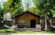 Tienda safari Villatent Wood en Camping Il Poggetto, Italia, con hamaca y un entorno verde natural.