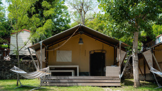 Safari-Zelt Villatent Wood auf dem Campingplatz Il Poggetto in Italien mit Veranda und Hängematte.