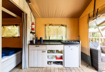 Coin cuisine d'une tente safari avec réchaud, mini-frigo, rangements et vue sur terrasse à Villatent Wood.