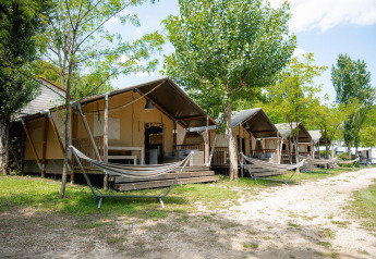 Safari-Zelte mit Hängematten bei Villatent Wood auf Camping Il Poggetto, umgeben von Bäumen in Italien.