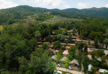 Luftaufnahme von Safari-Zelten Villatent Wood auf Camping Il Poggetto, umgeben von grüner Hügellandschaft.