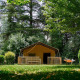 Safaritent Villatent Wood op Camping Lestaubière in Frankrijk, omgeven door bomen en groen gras.