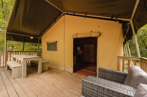 Safaritent Villatent Wood op Camping Lestaubière in Frankrijk met houten terras, bank en picknicktafel.