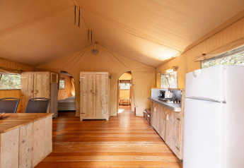 Vista interna della tenda safari Villatent Wood al Camping Lestaubière in Francia con cucina e arredamento.