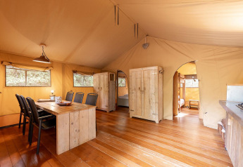 Interno della tenda safari Villatent Wood al Camping Lestaubière in Francia con arredi rustici in legno.