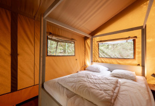 Interno di una tenda safari Villatent Wood con letto matrimoniale, due finestre e luce naturale.
