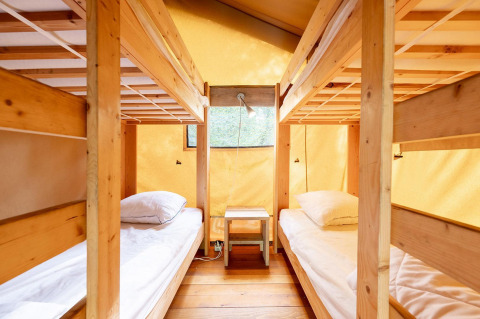 Binnenkant van een safaritent met twee houten stapelbedden bij Villatent Wood, Camping Lestaubière, Frankrijk.