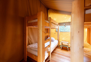 Interieur van het Villatent Wood safaritent met houten stapelbedden, houten vloer en veel daglicht.