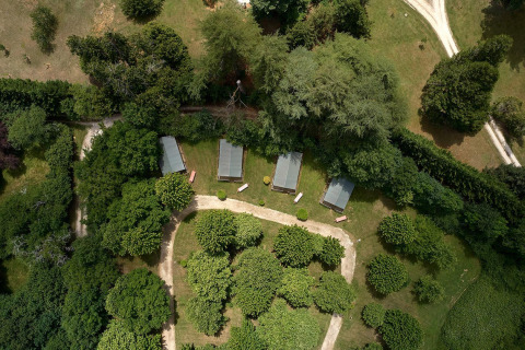Vista aérea de las tiendas safari Villatent Wood en Camping Lestaubière, rodeadas de árboles en Francia.