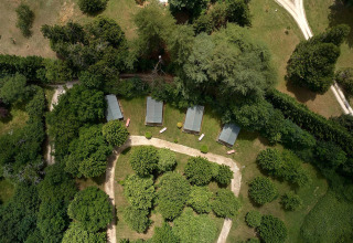 Vista aérea de las tiendas safari Villatent Wood en Camping Lestaubière, rodeadas de árboles en Francia.