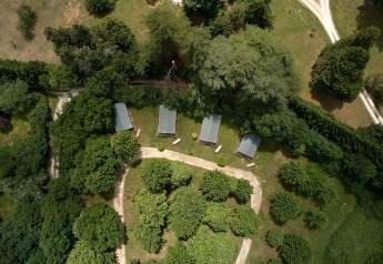Vista aerea delle tende safari Villatent Wood al Camping Lestaubière, circondate da alberi in Francia.
