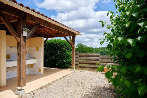 Espace de lavage extérieur couvert avec éviers carrelés à Villatent Wood, Camping Lestaubière, France.