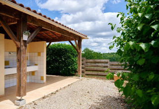 Zona de lavado exterior cubierta con azulejos y plantas en Villatent Wood, Camping Lestaubière, Francia.