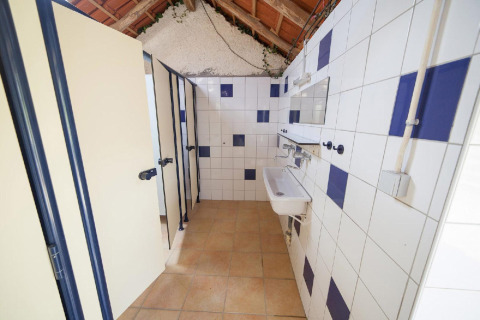 Gemeenschappelijk sanitair met douches en wastafels bij Villatent Wood, Camping Lestaubière, Frankrijk.