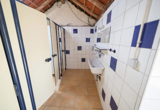 Gemeenschappelijk sanitair met douches en wastafels bij Villatent Wood, Camping Lestaubière, Frankrijk.