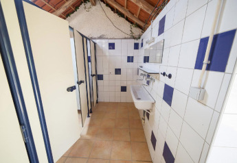 Communal bathroom with shower stalls and sinks at Villatent Wood, Camping Lestaubière, France.